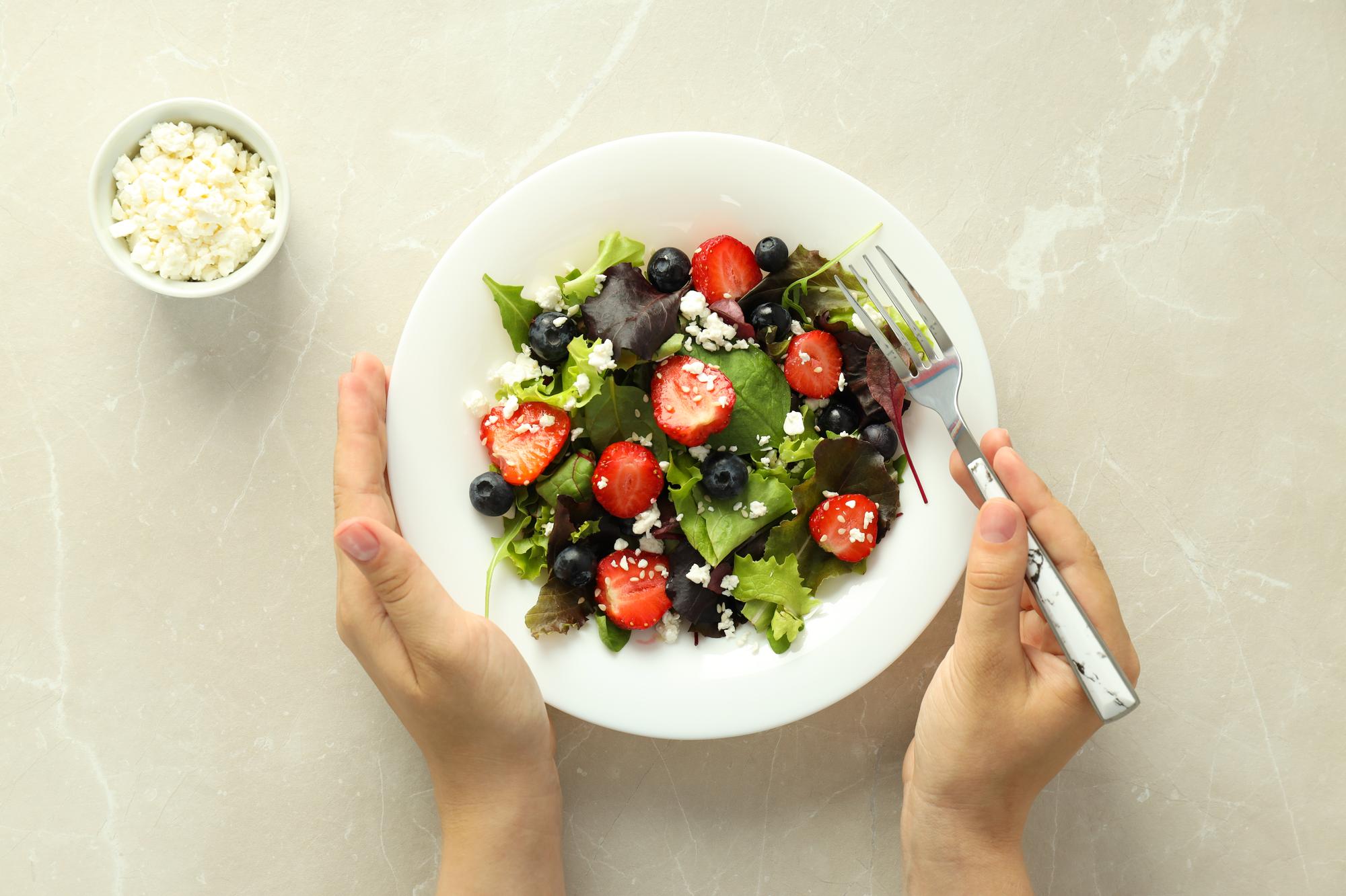 hands plating a composed seasonal salad